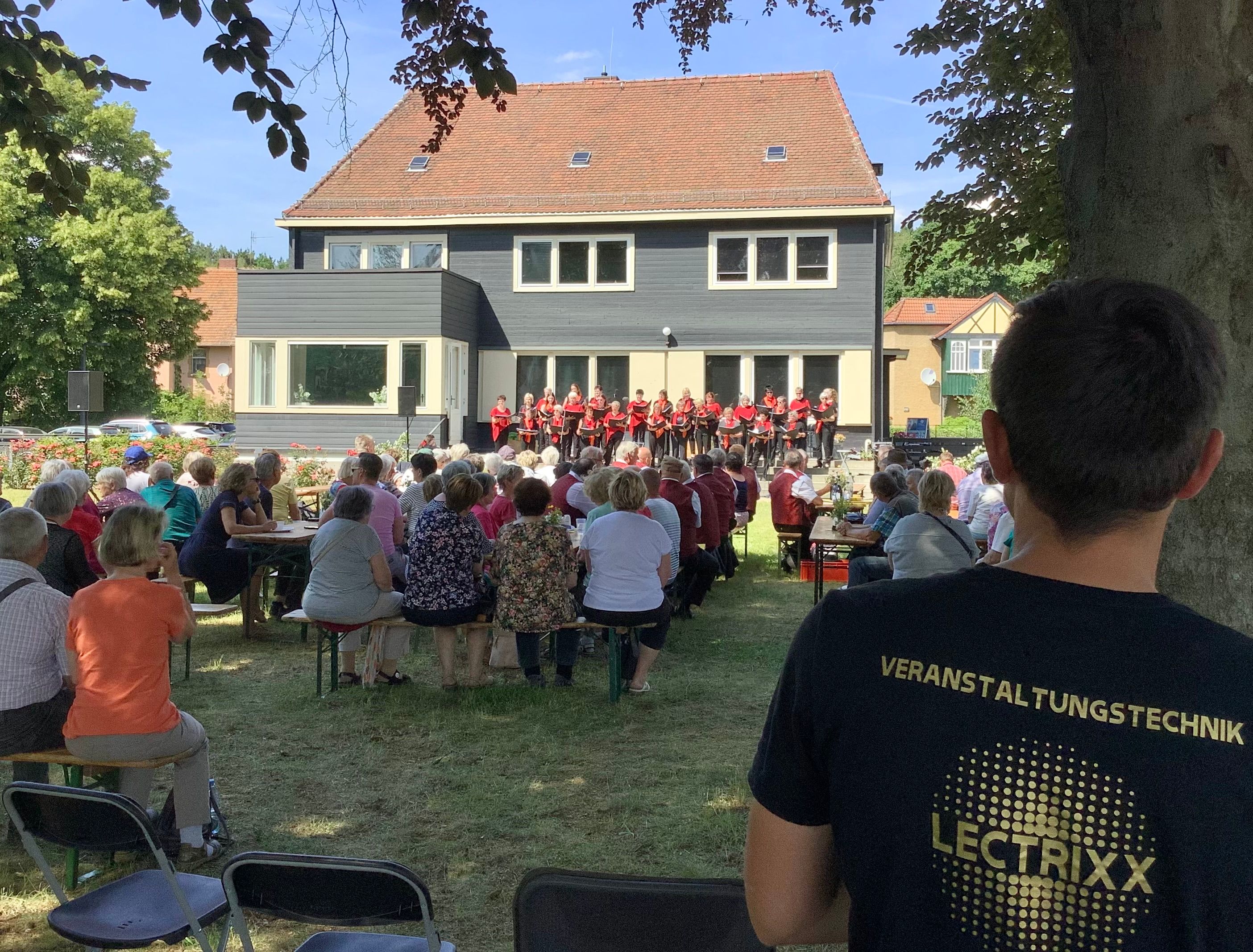 Open-Air-Konzert vor einem Gebäude, im Vordergrund ein Techniker im LECTRIXX-Shirt