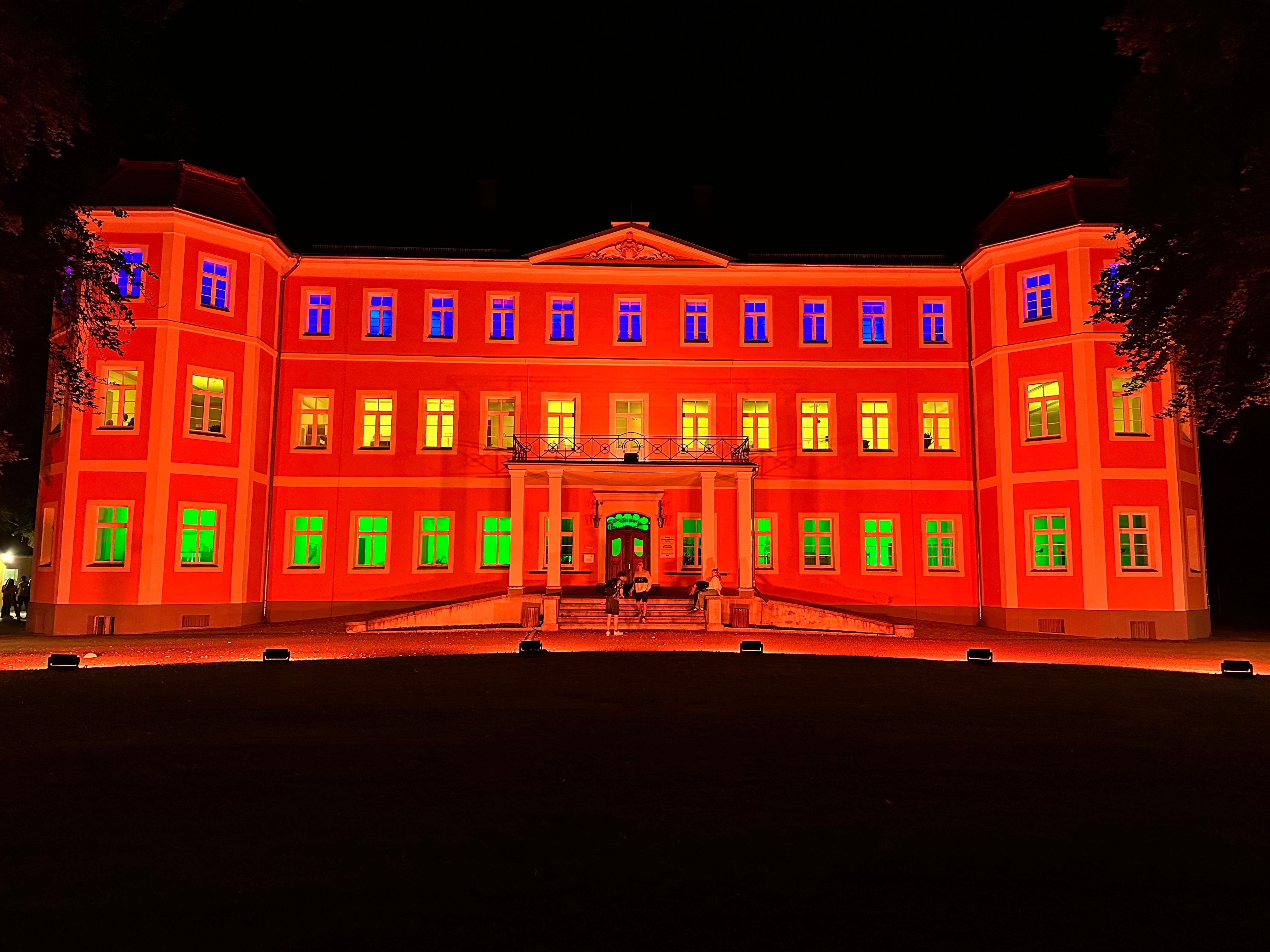 Rot und grün angestrahltes Schloss bei Nacht