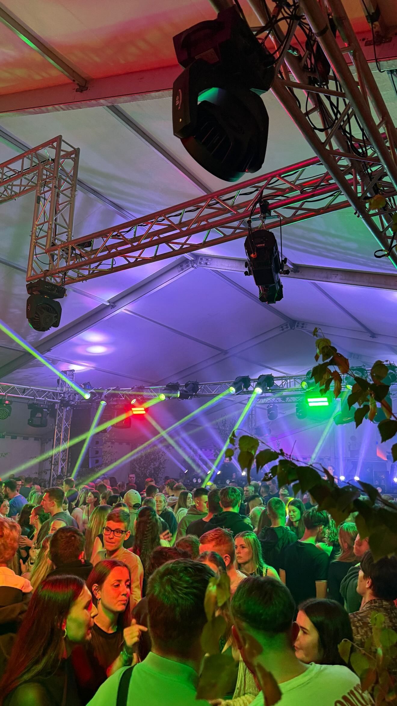Moving Head an einer rot angestrahlten Traverse, grüne Laserstrahlen über dem Publikum im Festzelt in Horka