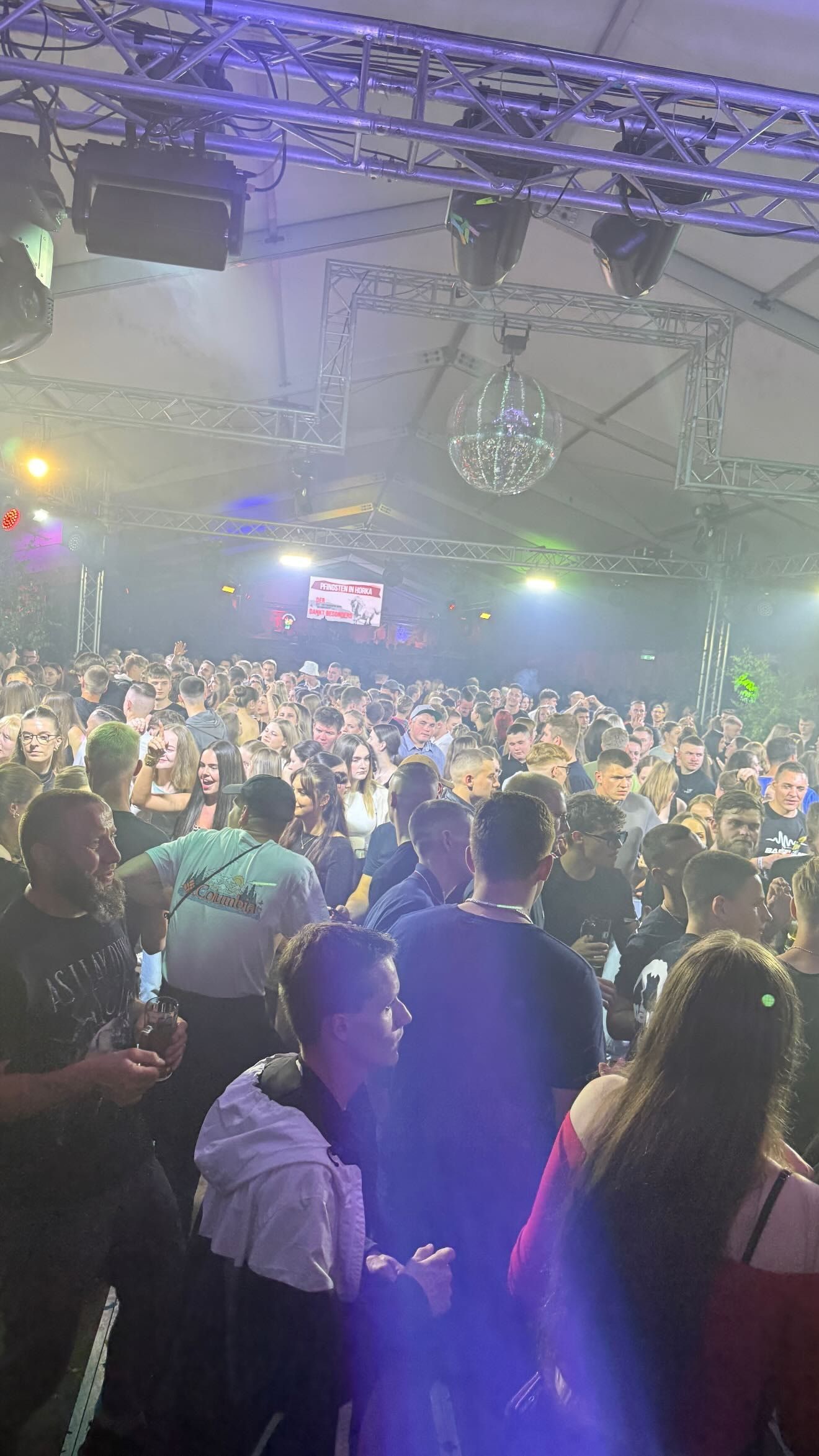 Volles Festzelt bei Pfingsten in Horka, darüber ein Traversen-Rig mit Moving Heads und Spiegelkugel im Nebel